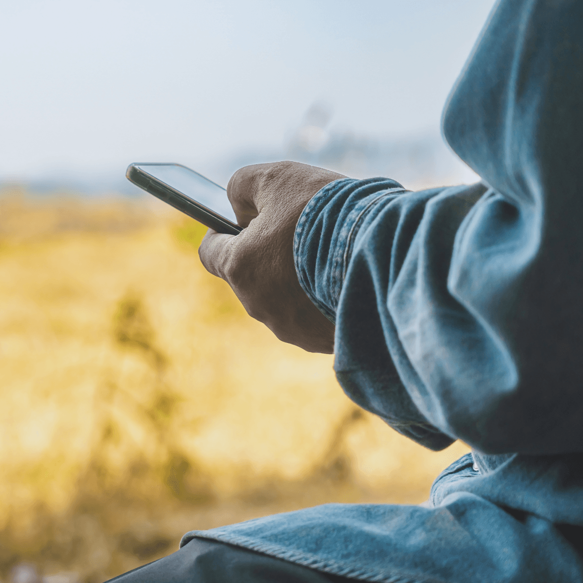 Farmer checking phone in a hay field